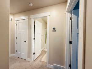 Hall featuring baseboards and light colored carpet