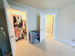 Carpeted bedroom featuring a walk in closet and baseboards