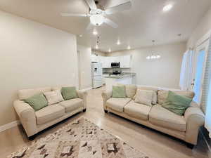 Living room with a chandelier, ceiling fan, light wood-type flooring, and recessed lighting