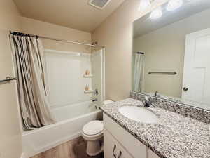 Bathroom featuring shower / tub combo with curtain, vanity, and dark wood-type flooring