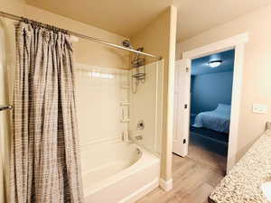 Ensuite bathroom with vanity, shower / tub combo with curtain, a textured ceiling, and light wood-style floors