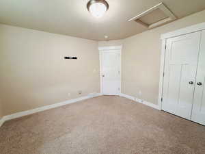 Unfurnished bedroom featuring attic access, carpet, a closet, and a textured ceiling