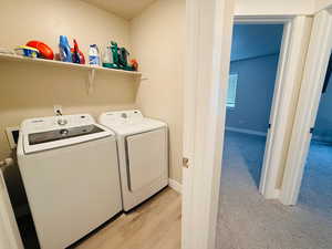 Laundry area with washer and clothes dryer and light wood-type flooring