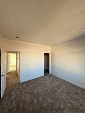 Bedroom 1 with a walk in closet, dark carpet, and a textured ceiling