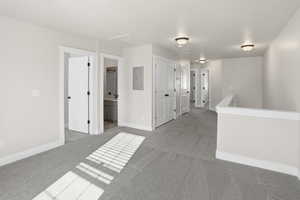 Unfurnished room featuring light colored carpet, electric panel, and attic access