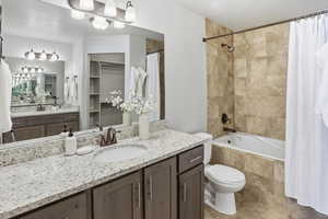 Full bathroom featuring vanity, tiled shower / bath combo, and a spacious closet