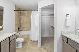 Full bathroom with vanity, tiled shower / bath, and a walk in closet