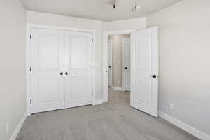 Unfurnished bedroom with light colored carpet and a closet