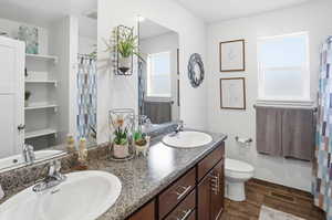 Bathroom featuring dark wood-type flooring, a shower with curtain, and double vanity