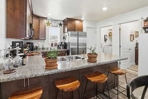 Kitchen with a kitchen breakfast bar, freestanding refrigerator, a peninsula, light wood-style floors, and recessed lighting