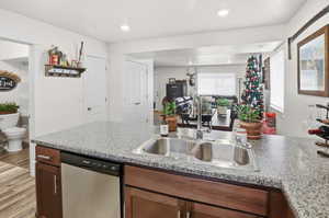 Kitchen with dishwasher, light wood-style flooring, light countertops, open floor plan, and recessed lighting