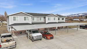 View of front of house with covered parking, a shingled roof, and stone siding