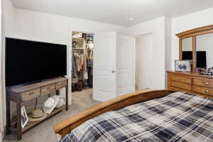 Bedroom with a spacious closet and light colored carpet