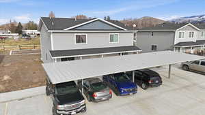 View of front of property featuring covered parking, roof with shingles, a residential view, and a mountain view