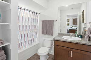 Bathroom featuring vanity, shower / tub combo with curtain, and dark wood-style flooring