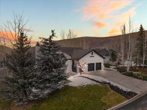 View of front of home with concrete driveway, a garage, a chimney, a yard, and stucco siding