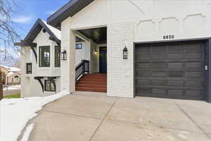 Property entrance with brick siding, concrete driveway, and a garage