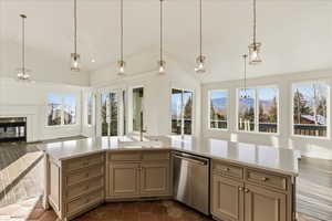 Kitchen with a chandelier, vaulted ceiling, hanging light fixtures, open floor plan, and dishwasher
