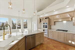 Kitchen featuring lofted ceiling, backsplash, stainless steel appliances, hanging light fixtures, and glass insert cabinets