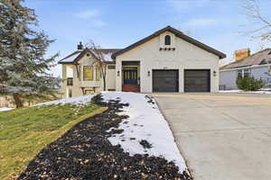 View of front of house featuring a chimney, concrete driveway, brick siding, and a garage