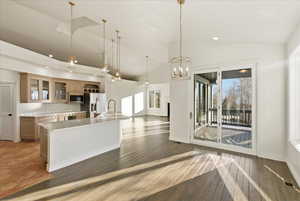 Kitchen with glass insert cabinets, light countertops, a center island with sink, pendant lighting, and open floor plan