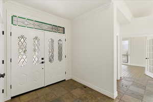 Foyer entrance featuring stone tile flooring and crown molding