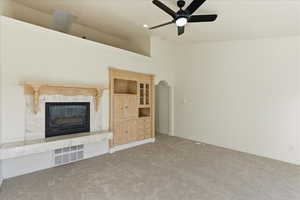 Unfurnished living room with a premium fireplace, carpet, ceiling fan, recessed lighting, and a high ceiling