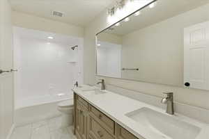 Full bath featuring double vanity, tub / shower combination, and light marble finish flooring
