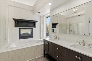 Full bathroom featuring ornamental molding, double vanity, a stall shower, a garden tub, and dark wood-type flooring