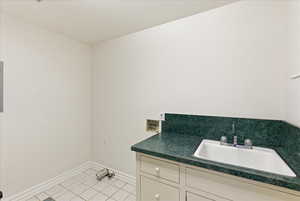 Laundry area featuring light tile patterned floors, hookup for a washing machine, and cabinet space