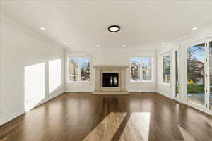 Unfurnished living room with crown molding, a fireplace, dark wood-style flooring, and recessed lighting