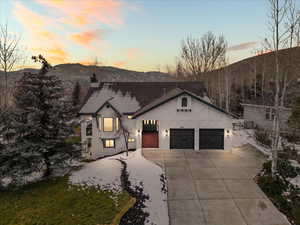 View of front of property with driveway, stucco siding, a chimney, and a garage