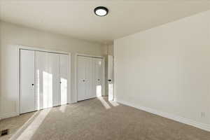Unfurnished bedroom with multiple closets and carpet floors