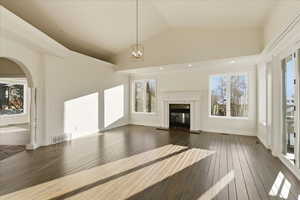 Unfurnished living room with vaulted ceiling, a fireplace, dark wood-style floors, and a chandelier