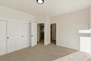 Unfurnished bedroom with a closet, connected bathroom, and light colored carpet