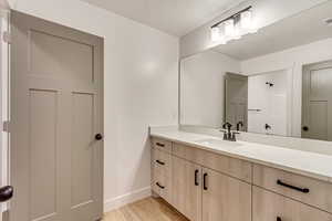 Full bath featuring vanity, light wood-type flooring, and a textured ceiling