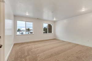 Unfurnished room featuring light carpet and baseboards