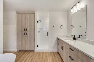 Bathroom with vanity, a shower stall, light wood-style flooring, a freestanding tub, and a textured ceiling
