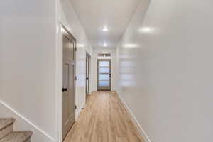 Hallway with light wood-style floors and stairway