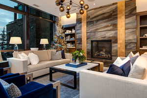 Living room with built in shelves, a fireplace, a chandelier, and a wall of windows