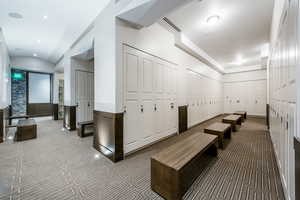 Hallway featuring dark colored carpet, wainscoting, and vaulted ceiling