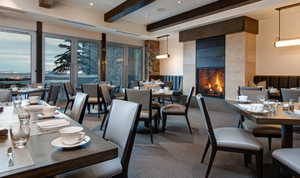 Dining space with a tile fireplace, beam ceiling, carpet flooring, and recessed lighting