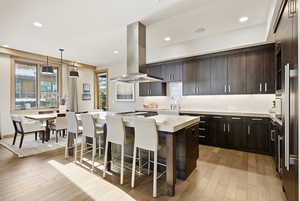 Kitchen featuring a kitchen island, pendant lighting, modern cabinets, a kitchen breakfast bar, and dark brown cabinets