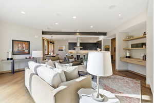 Living area with built in desk, light wood-style flooring, and recessed lighting