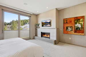 Bedroom featuring wallpapered walls, a glass covered fireplace, carpet, access to outside, and recessed lighting