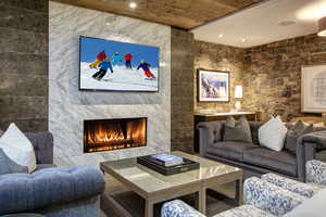Living area featuring a tile fireplace, recessed lighting, tile walls, and wood ceiling