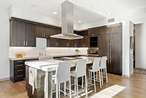 Kitchen with dark brown cabinets, island range hood, modern cabinets, a breakfast bar, and a center island
