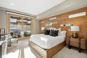 Bedroom featuring wood walls, light colored carpet, access to exterior, and recessed lighting