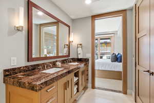 Ensuite bathroom featuring double vanity and light tile patterned flooring