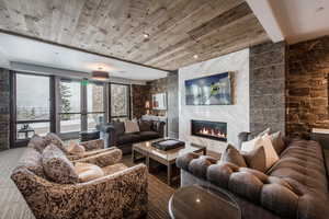 Living area featuring a fireplace, wood ceiling, and tile walls
